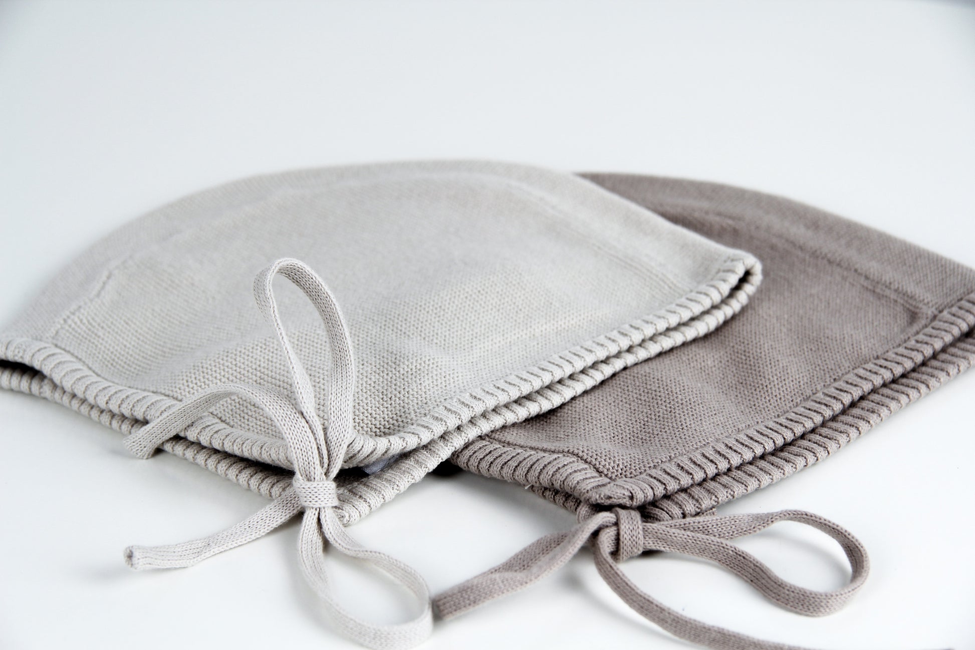 Unisex Strick Bonnet / Haube von Kindly für den minimalistischen Look in den Farben Haselnuss und Beige. Detailfoto auf die zubindbaren Schnurenden.